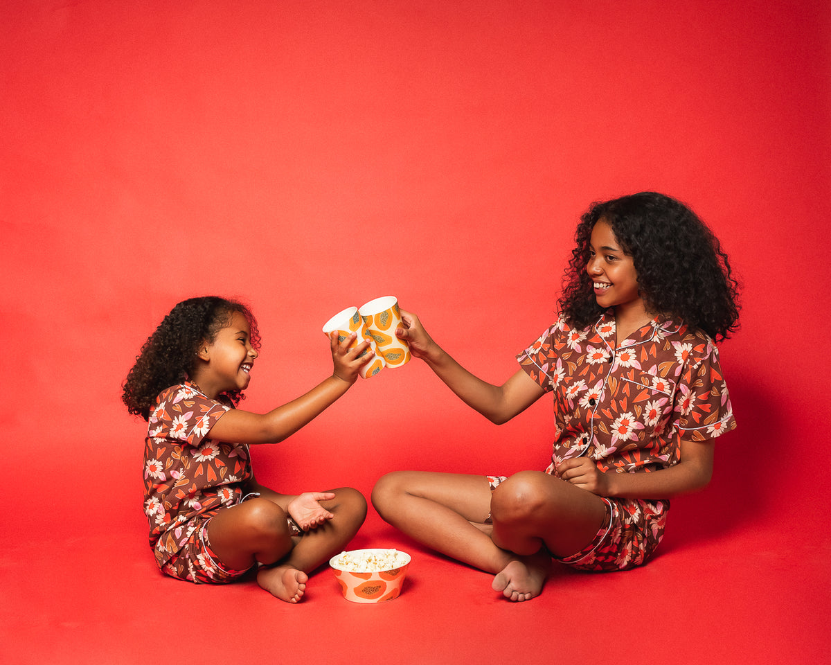 Two children sharing a playful moment in matching floral COCOLILI outfits