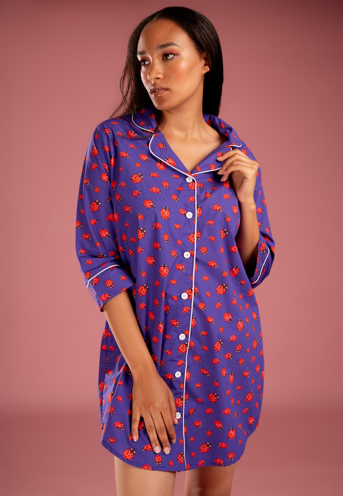 a woman in a purple and red lady bird printed night shirt