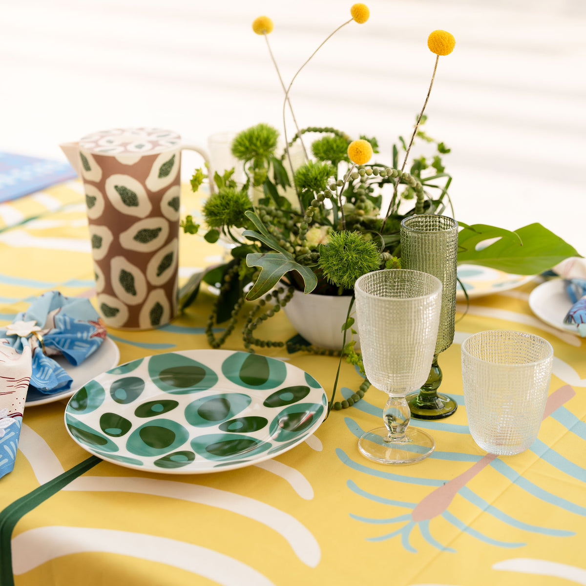 Yellow COCOLILI table linen with green printed plates and fresh flowers