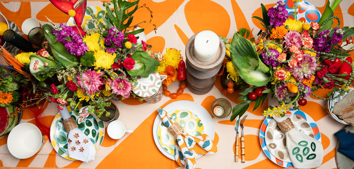 Orange COCOLILI table linen with abundant flowers and colourful dinnerware