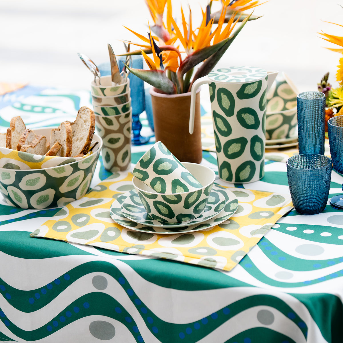 Green and white COCOLILI dinnerware with a jug, bowl, cups and plates on a coordinated table